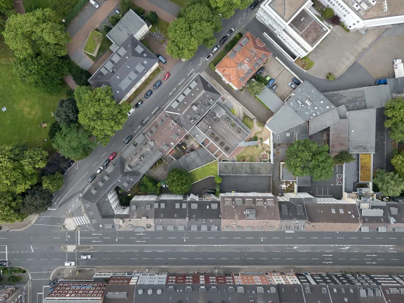 Luftbildaufnahme einer urbanen Straßenkreuzung in Essen mit mehrspurigen Fahrbahnen, Wohnbebauung, Grünanlagen und moderner Verkehrsinfrastruktur. Die Drohnenaufnahme zeigt die charakteristische Stadtarchitektur des Ruhrgebiets aus der Vogelperspektive.
